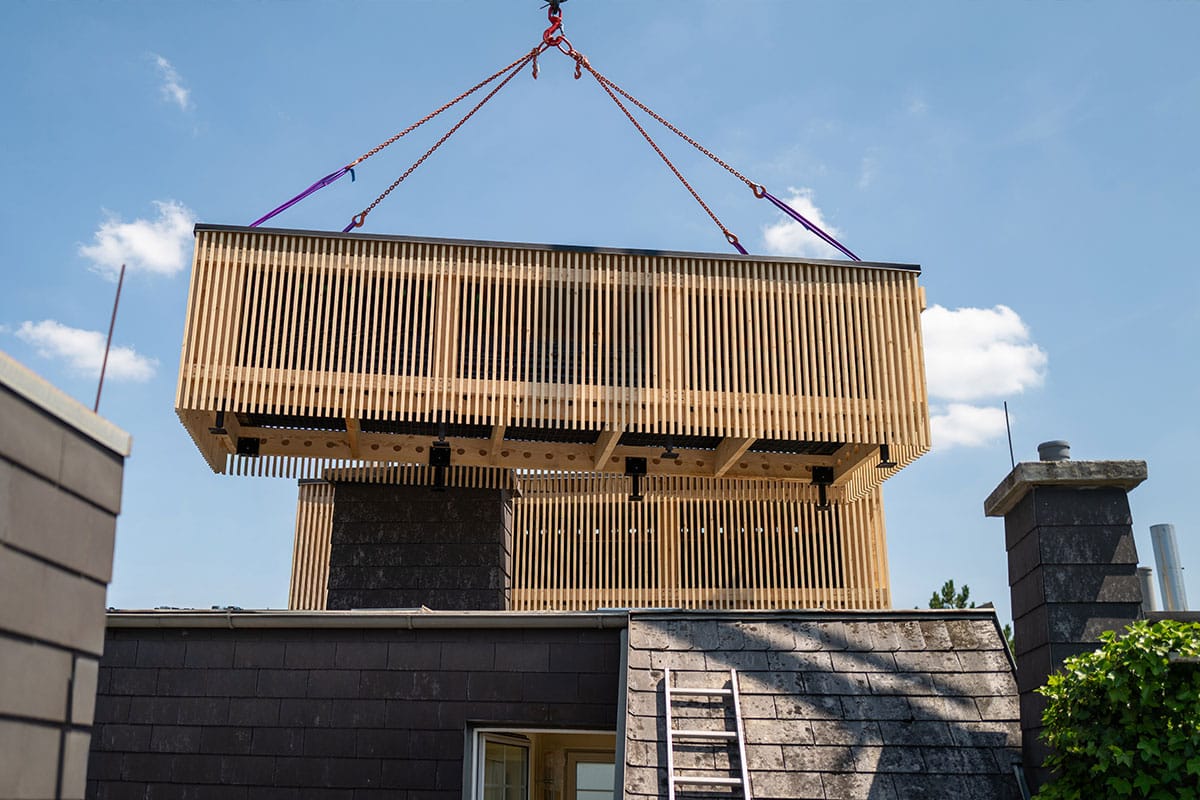 Prefabricated, timber-clad module just before being set down on the roof